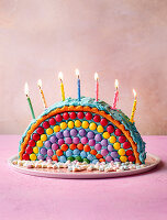 A rainbow cake decorated with marshmallows and Smarties
