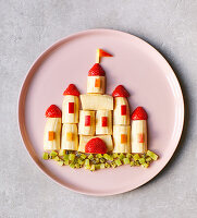 A fruit castle made with bananas, strawberries and apple