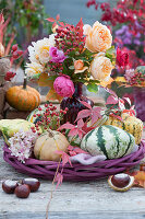 Bouquet of roses and rose hips between pumpkins, hydrangea blossom, wild vine tendril and chestnuts as decoration