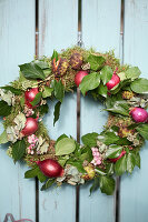 Autumn wreath with moss, ivy leaves, red onions, hydrangea blossoms, snowberries and chestnut shells