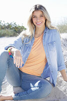 A young blonde woman wearing denim and an apricot top