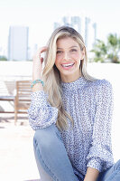 A young blonde woman wearing a blue-and-white patterned top and jeans