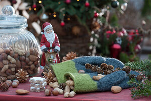 Arrangement mit Weihnachtsmann, Fäustlingen, Nüssen, Zapfen, Zimtsternen, Tannenbäumchen aus Holz, Tannenzweigen und Blüten von Christrose