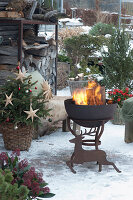 Verschneite, weihnachtliche Terrasse mit Feuerschale und Weihnachtsbaum, Hirschsilhouette aus Edelrost