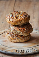 Seeded bread rolls stacked on an antique bread board