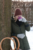 Frau trinkt heißen Punsch im verschneiten Garten