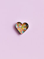 A heart-shaped cutter filled with colourful sugar letters