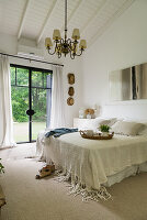 Double bed with white bedspread in a country bedroom