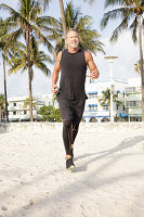 A grey-haired man jogging in black sports clothes