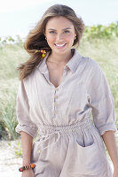 A young, long-haired woman wearing a beige linen blouse and shorts