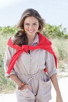 A young, long-haired woman wearing a beige linen blouse with a red jumper over her shoulder