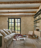 Bequeme Sofa und Couchtische, Designerstuhl und offenes Regal im Wohnraum mit sandfarbener Wand