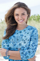 A young woman with long hair wearing a blue patterned dress