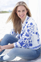 A long-haired blonde woman wearing jeans and a blue-and-white jacket