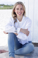 A long-haired blonde woman wearing a white shirt blouse and jeans