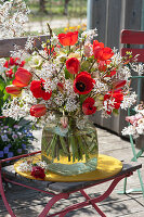 Frühlingsstrauß aus roten Tulpen, Zweigen von Felsenbirne und Zierkirsche und Lenzrosen