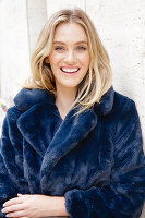 A young blonde woman wearing a blue faux fur coat