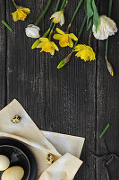 Daffodils, ranunculus and parrot tulips on black boards