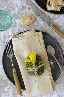 Moss egg with daffodil on napkin on rustic table setting