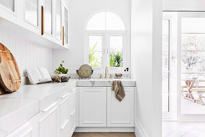 Weiße Einbauküche in L-Form mit Rundbogenfenster