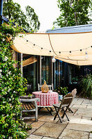 Round table and wooden chairs under awning on terrace