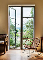 Bamboo rocking chair next to French windows with garden access