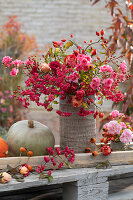 Rosarot-pinker Herbststrauß aus Rosen, Hagebutten und Zweigen vom Pfaffenhütchen
