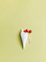 A paper bag of fresh tomatoes with chips forks