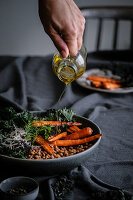 Vegan buckwheat vegetable bowl being drizzled with olive oil