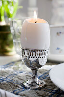 Egg-shaped candle in silver egg cup on an Easter table