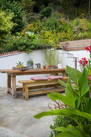 Outdoor seating area with wooden bench and table on natural stone tiles