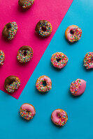 Donuts mit Glasur und Zuckerstreusel auf zweifarbigem Untergrund