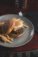 Breakfast burger with fried egg, cheddar cheese, ground bacon, beef patty, chips