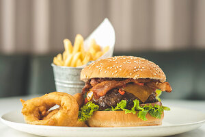 Cheeseburger mit Chili, Speck, Zwiebelringen und Pommes