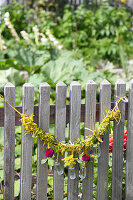 Purple pompom dahlias in glass bottles with garland of goldenrod on fence