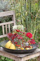 Bouquets of zinnias in glass containers with wreaths of berries