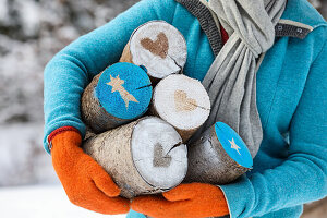 Frau trägt Holzstämme mit Weihnachtsmotiven