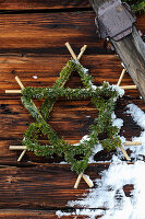 Star made of bamboo sticks and conifer branches on a wooden wall