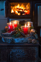 Lanterns with red candles on a Christmas decorated tree slice