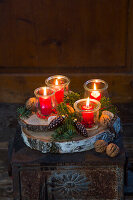 Lanterns with red candles on a Christmas decorated tree slice