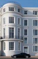 Graue und weiße Fassade eines georgianischen Hauses mit geparktem schwarzen Sportwagen an der Strandpromenade von St Leonards on Sea, East Sussex, UK