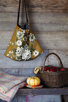 Rustic wooden panelling with haning floral bag a bench with pumpking and a blanket and basket filled with red apples