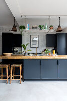 Modern kitchen unit in black with wooden accents and various indoor plants