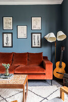 Wohnzimmer mit orangenem Samtsofa, Gitarre und Retro-Stehlampe