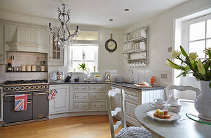 White country style kitchen with a wall mounted dish rack, and a dining area in the foreground
