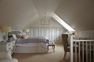 Spacious bedroom in the attic with built in wardrobes and light wood decorative paneled walls