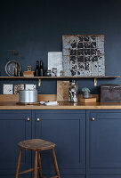 Dark blue kitchen cabinets with rustic decoration and wooden stool, dark blue wall