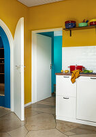 Kitchen with yellow walls, stone floor, metro tiles and white cupboards