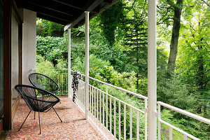 Balcony with black plastic wicker chairs and view of the forest