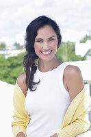 A dark-haired woman wearing a white top and a yellow cardigan